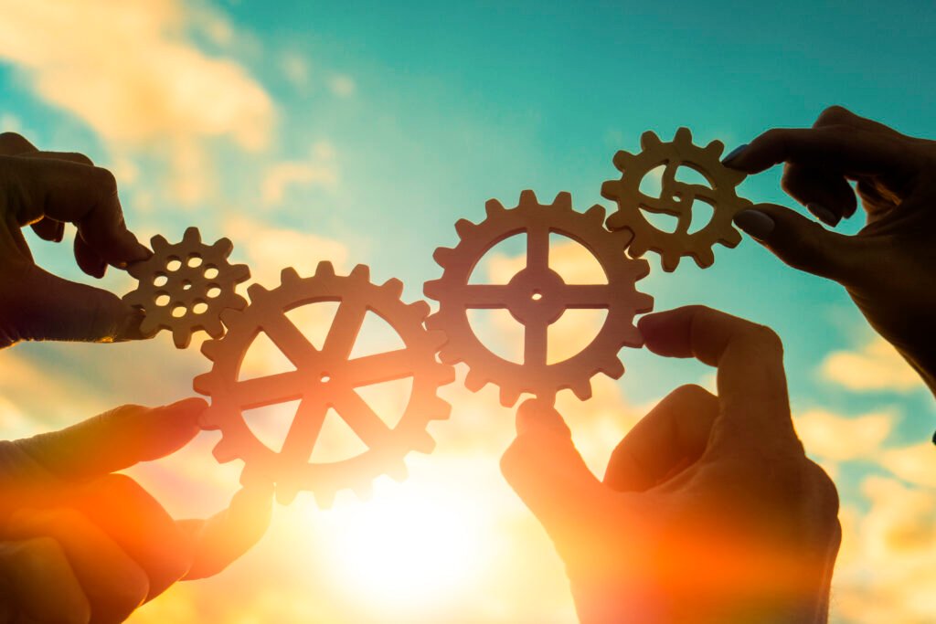 Four,Hands,Of,Businessmen,Connect,Gears,To,A,Puzzle,On